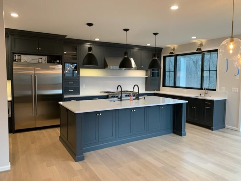 Modern Maryland kitchen with dark blue cabinets, oak floors, and pendant lighting above a large island.