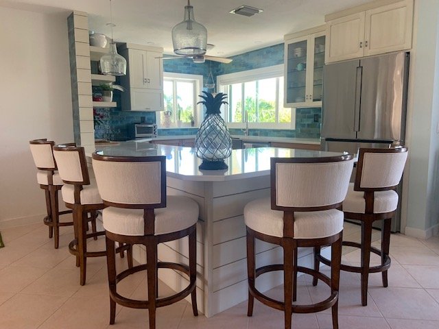 Coastal kitchen in Summerland Key, Florida with white cabinetry, blue backsplash, and island seating by Choice Custom Cabinetry & Design