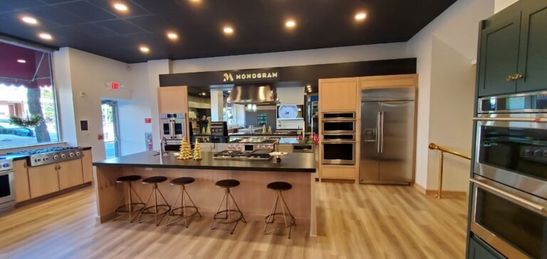 Modern kitchen display with deep blue cabinetry, brass hardware, and Café appliances by Choice Custom Cabinetry & Design.