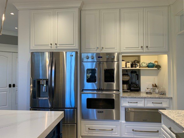 Modern kitchen display with teal cabinetry, brass hardware, and Café appliances by Choice Custom Cabinetry & Design.