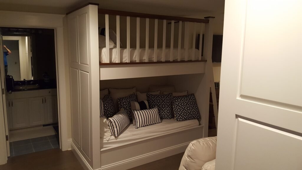 Custom built-in bunk beds with wood stairs, white cabinetry, and window bench seating by Choice Custom Cabinetry & Design in Pennsylvania.
