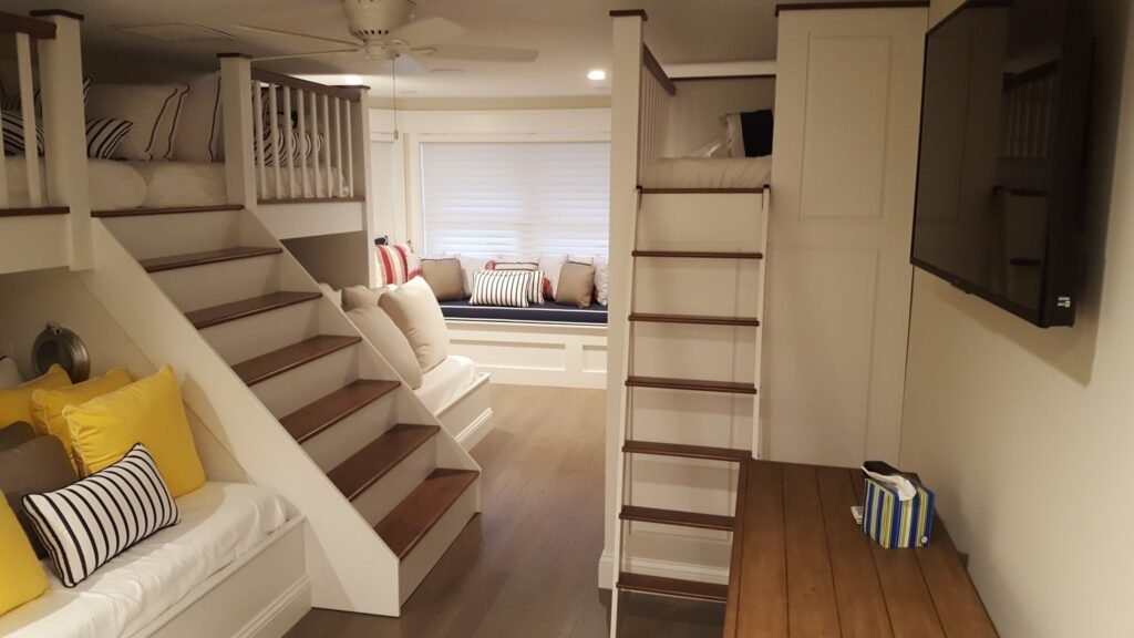 Custom built-in bunk beds with wood stairs, white cabinetry, and window bench seating by Choice Custom Cabinetry & Design in Pennsylvania.