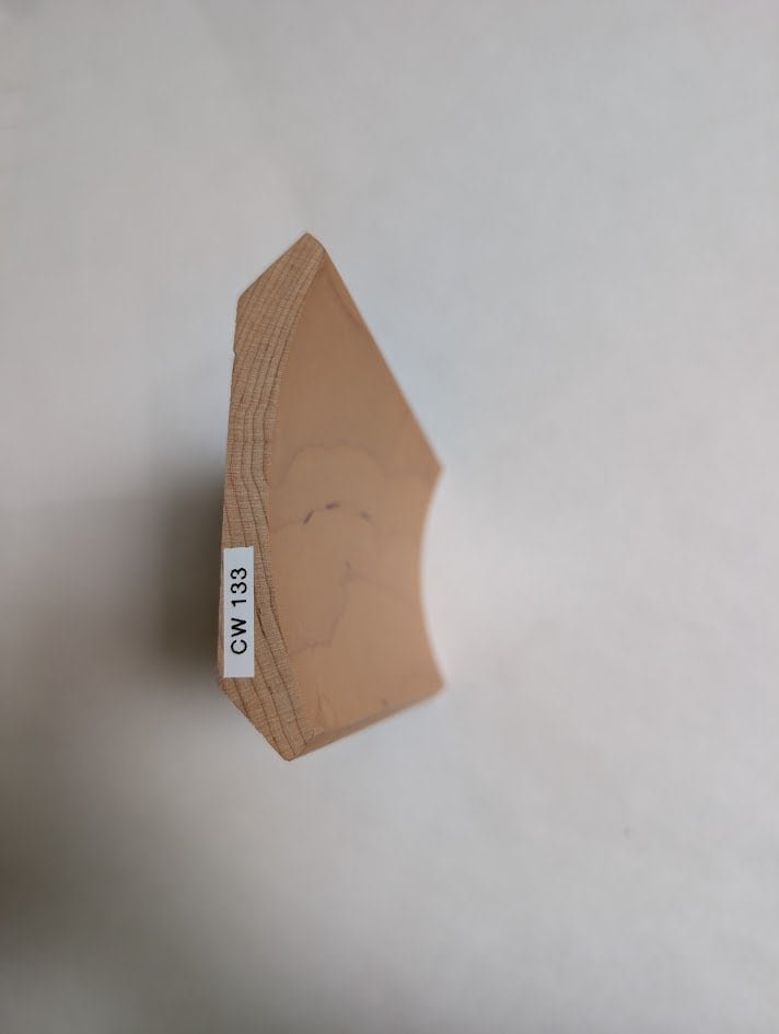 A close-up of a piece of wood with an angled edge, displaying a white label that reads GW-1333—highlighting the craftsmanship of a bespoke cabinetry manufacturer against a plain light background.