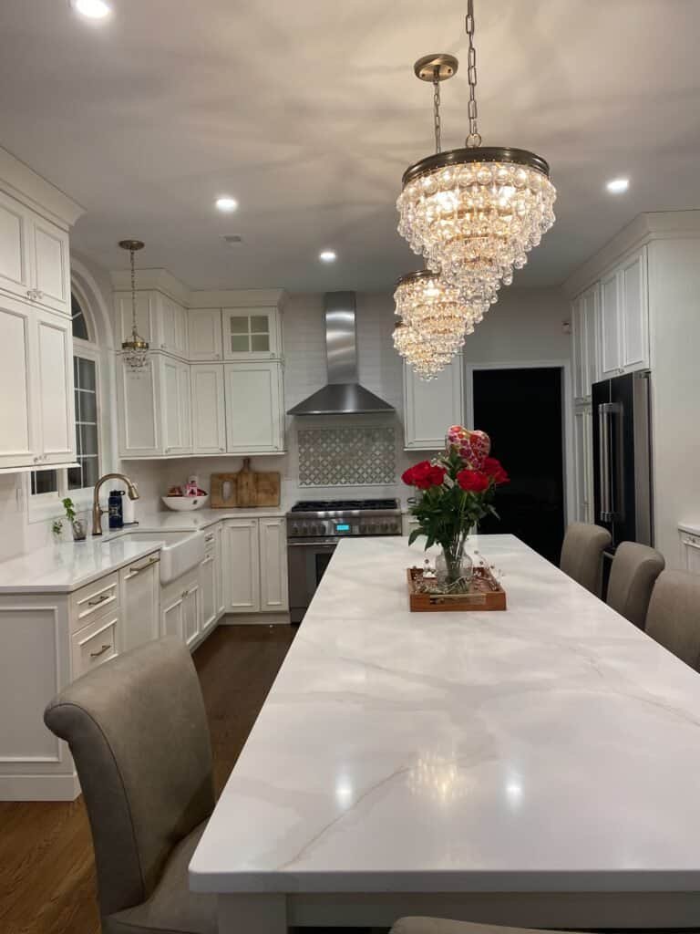 Elegant white kitchen cabinets with custom cabinetry and modern design, featuring a large marble island.