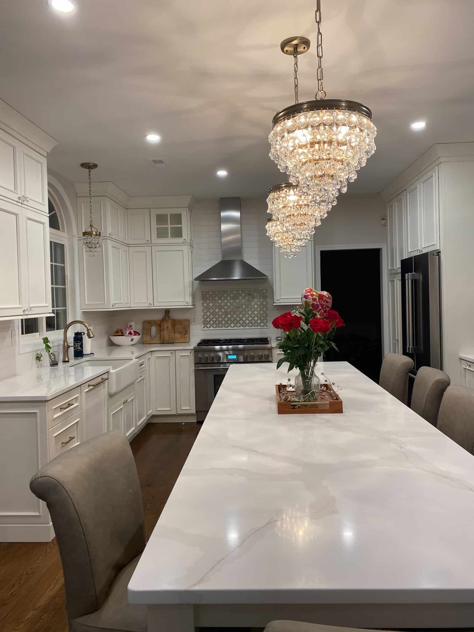 Elegant white kitchen cabinets with custom cabinetry and modern design, featuring a large marble island.