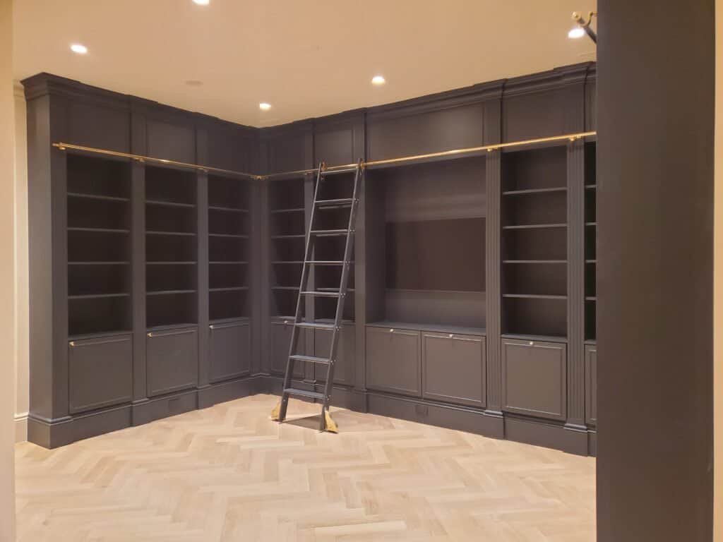 Custom floor-to-ceiling home library wall with rolling ladder and brass rail, Pennsylvania