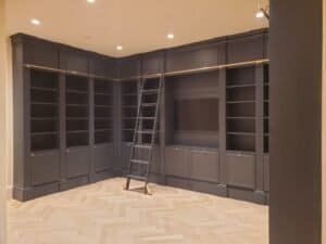 Custom floor-to-ceiling home library wall with rolling ladder and brass rail, Pennsylvania
